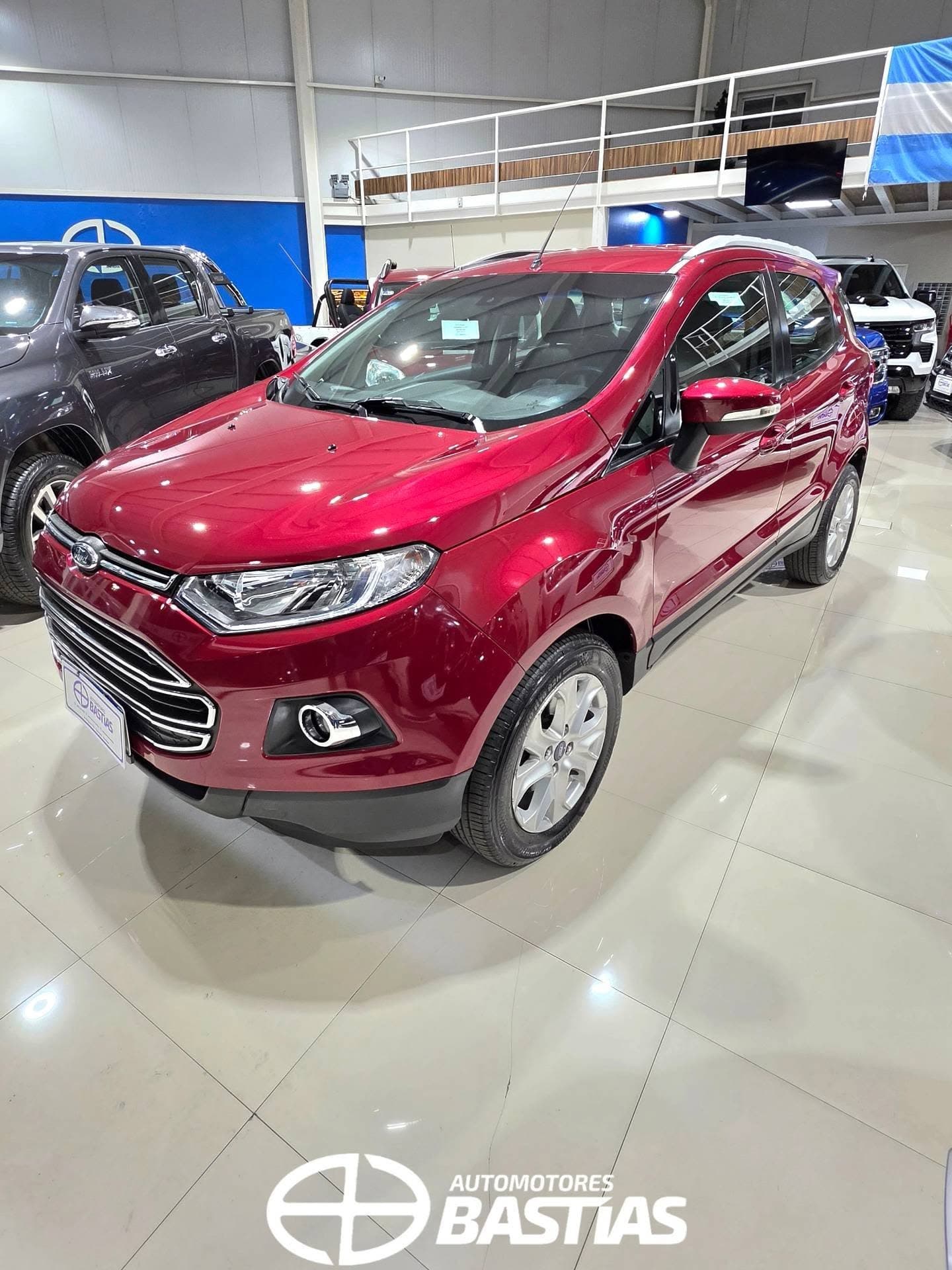 Salón de Automotores Bastías: pared azul de marca con el isotipo blanco y el piso brillante